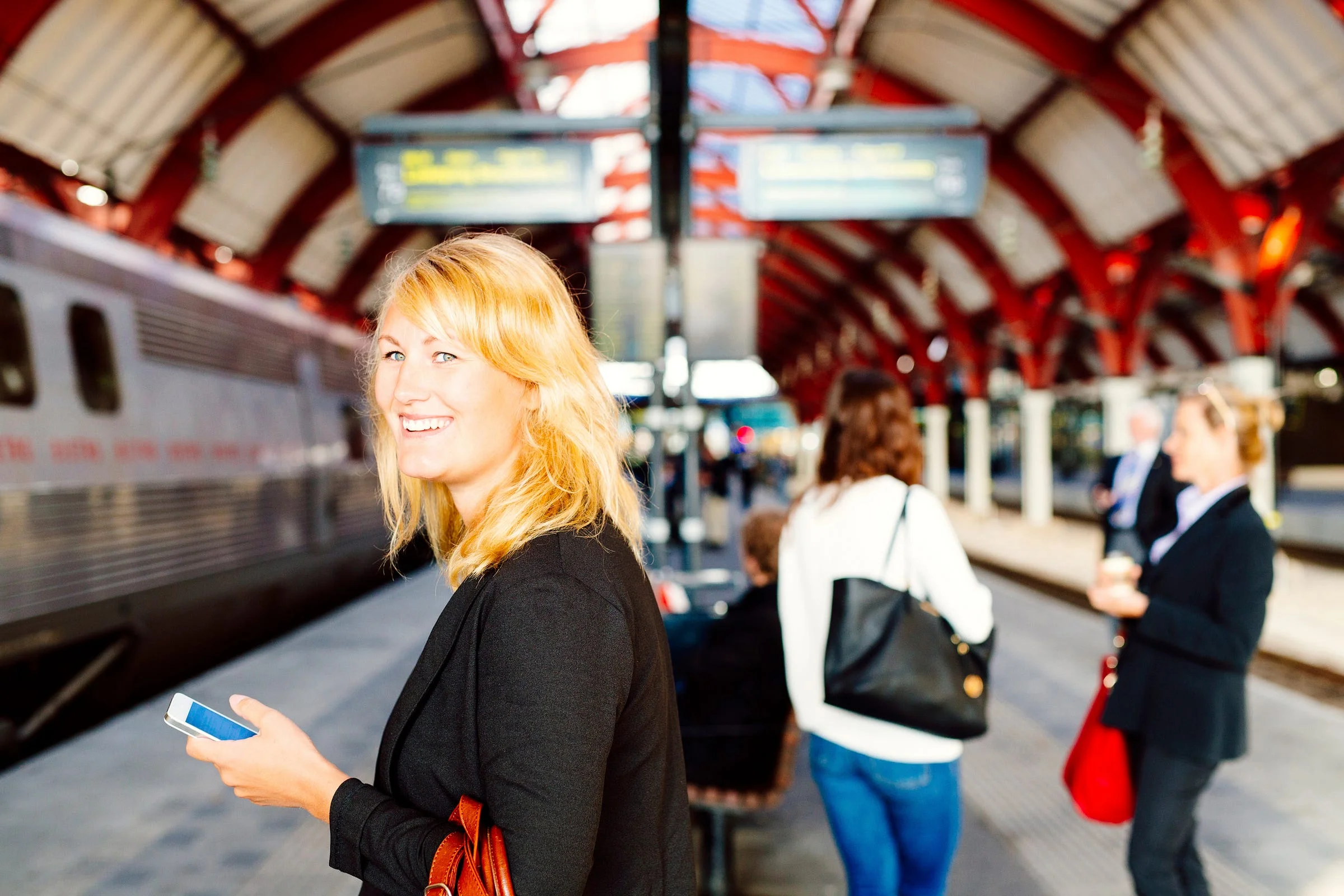 Travelers on a station platform watching a train pull in, the moment before boarding